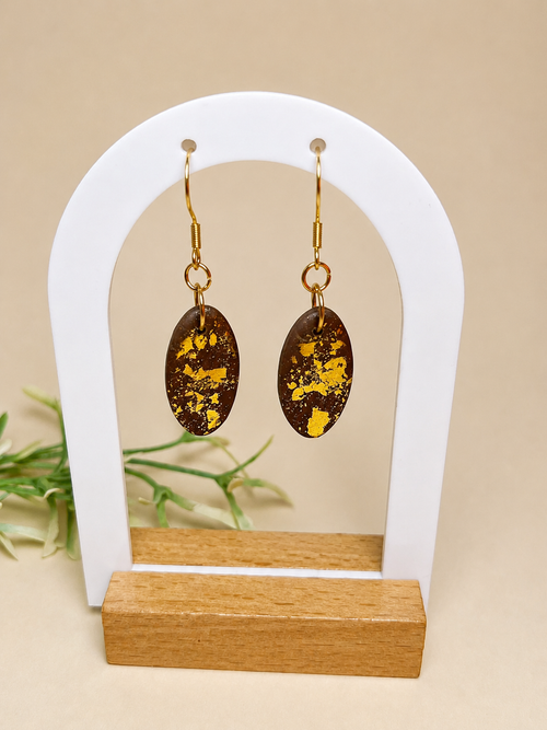 Pendientes Choco Glow de arcilla polimérica en dorado y marrón sobre expositor