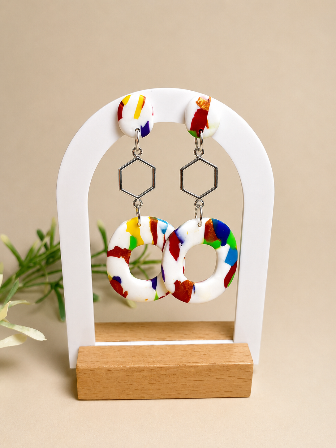 Pendientes Hex de arcilla polimérica en blanco, amarillo, rojo, naranja, verde y azul sobre expositor