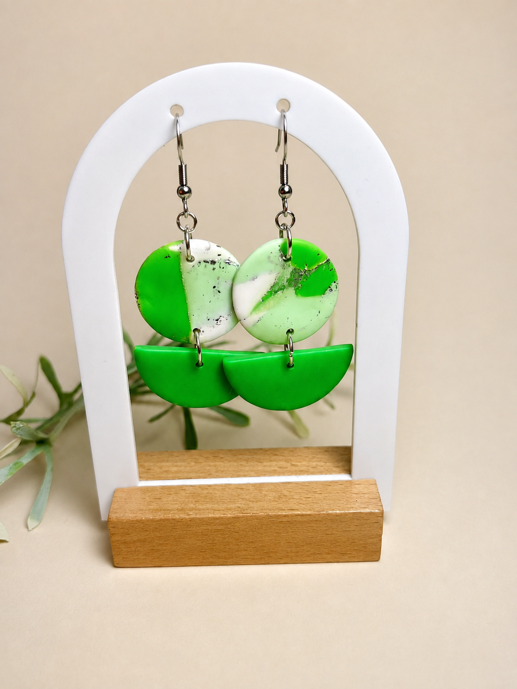 Pendientes Kiwi de arcilla polimérica en verde y blanco sobre expositor