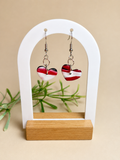 Pendientes Red Heart de arcilla polimérica en rojo, blanco y negro sobre expositor