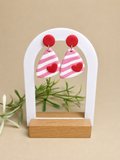 Pendientes Love Pop de arcilla polimérica en rosa, blanco y rojo sobre expositor