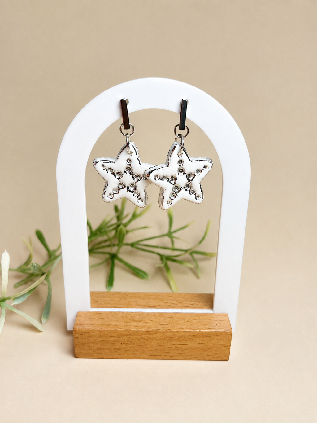 Pendientes Estrella Colgante White de arcilla polimérica en blanco y plateado sobre expositor