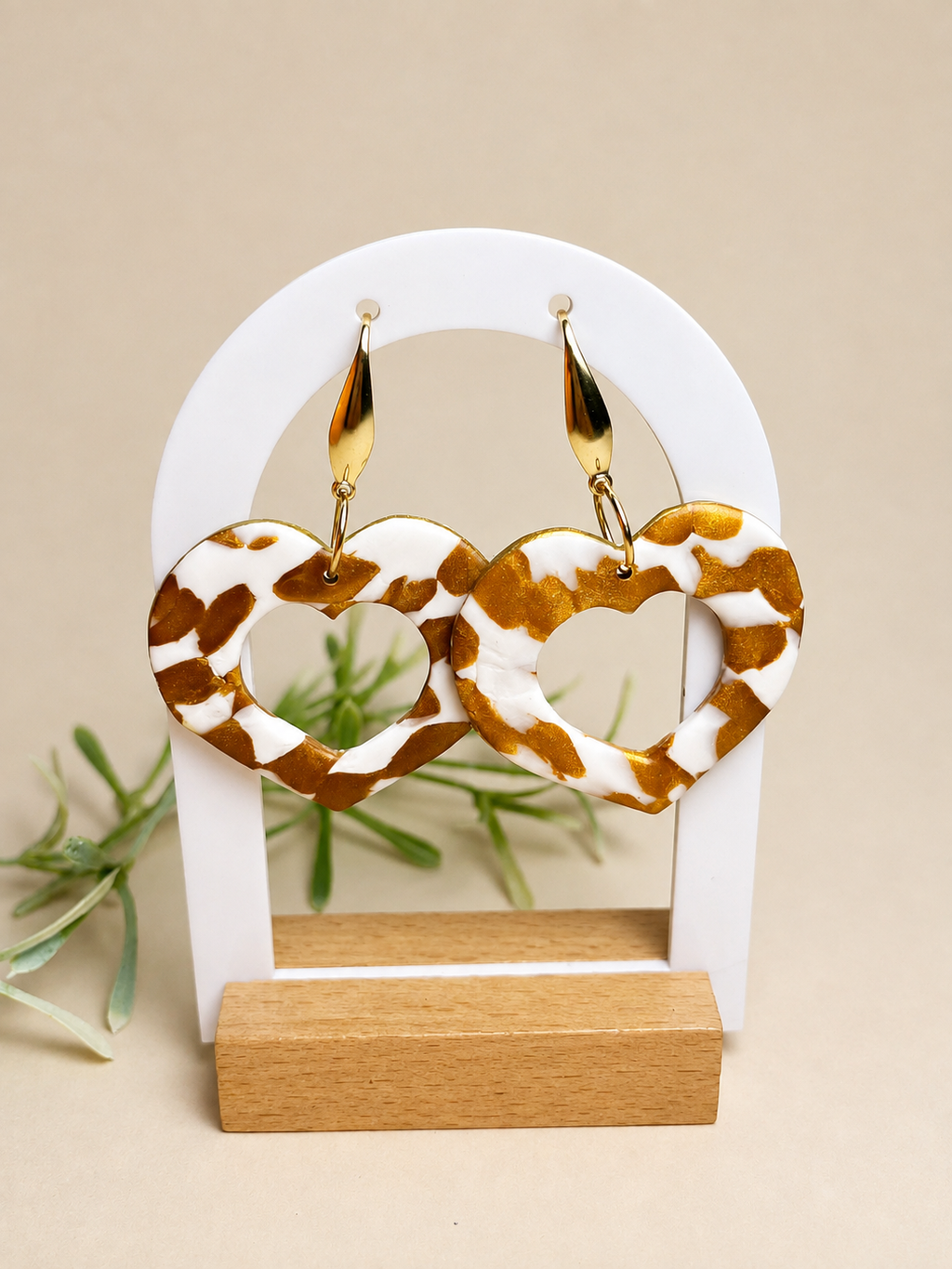 Pendientes Terra Beat de arcilla polimérica en dorado y blanco sobre expositor