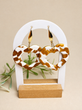Pendientes Terra Beat de arcilla polimérica en dorado y blanco sobre expositor