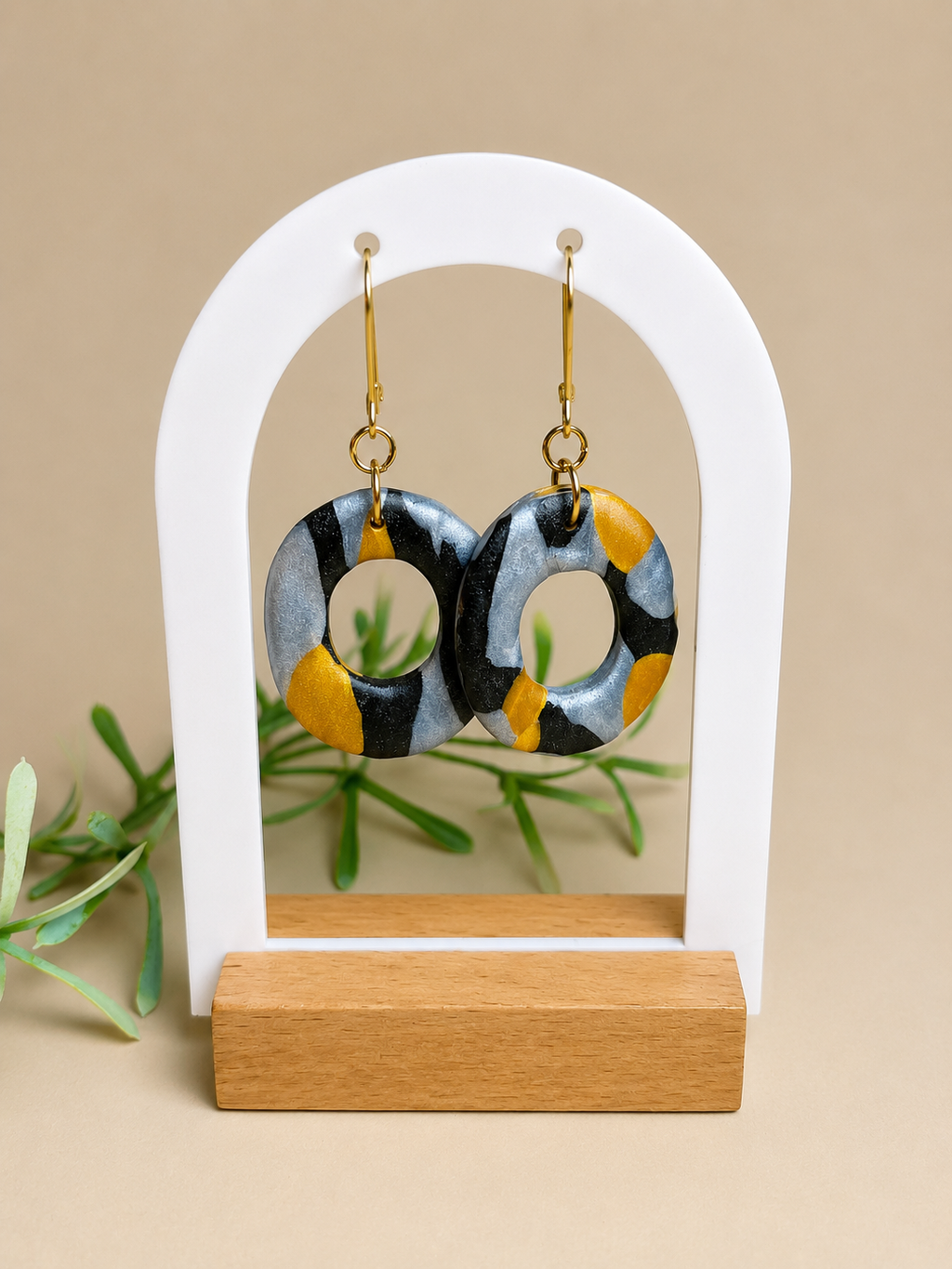 Pendientes Eclipse Ring de arcilla polimérica en negro, plateado y dorado sobre expositor