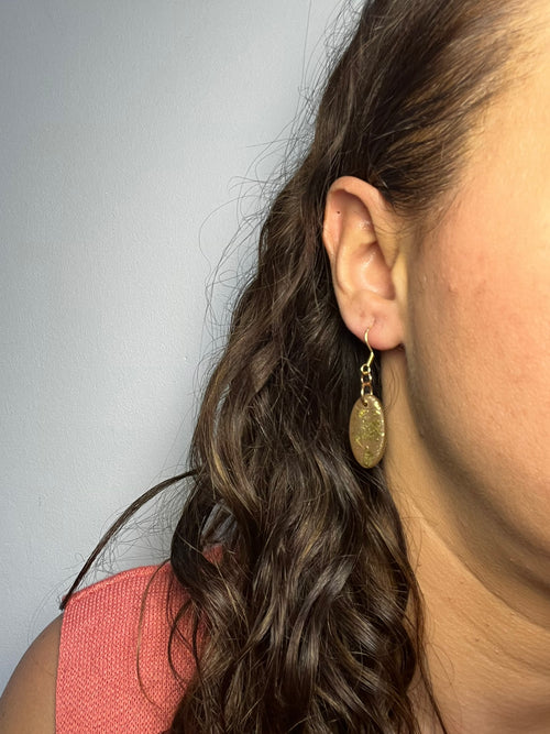 Pendientes Choco Glow de arcilla polimérica en dorado y marrón puestos en la oreja
