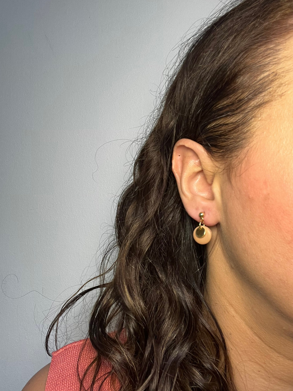 Pendientes Brillo de arcilla polimérica en dorado y beige puestos en la oreja