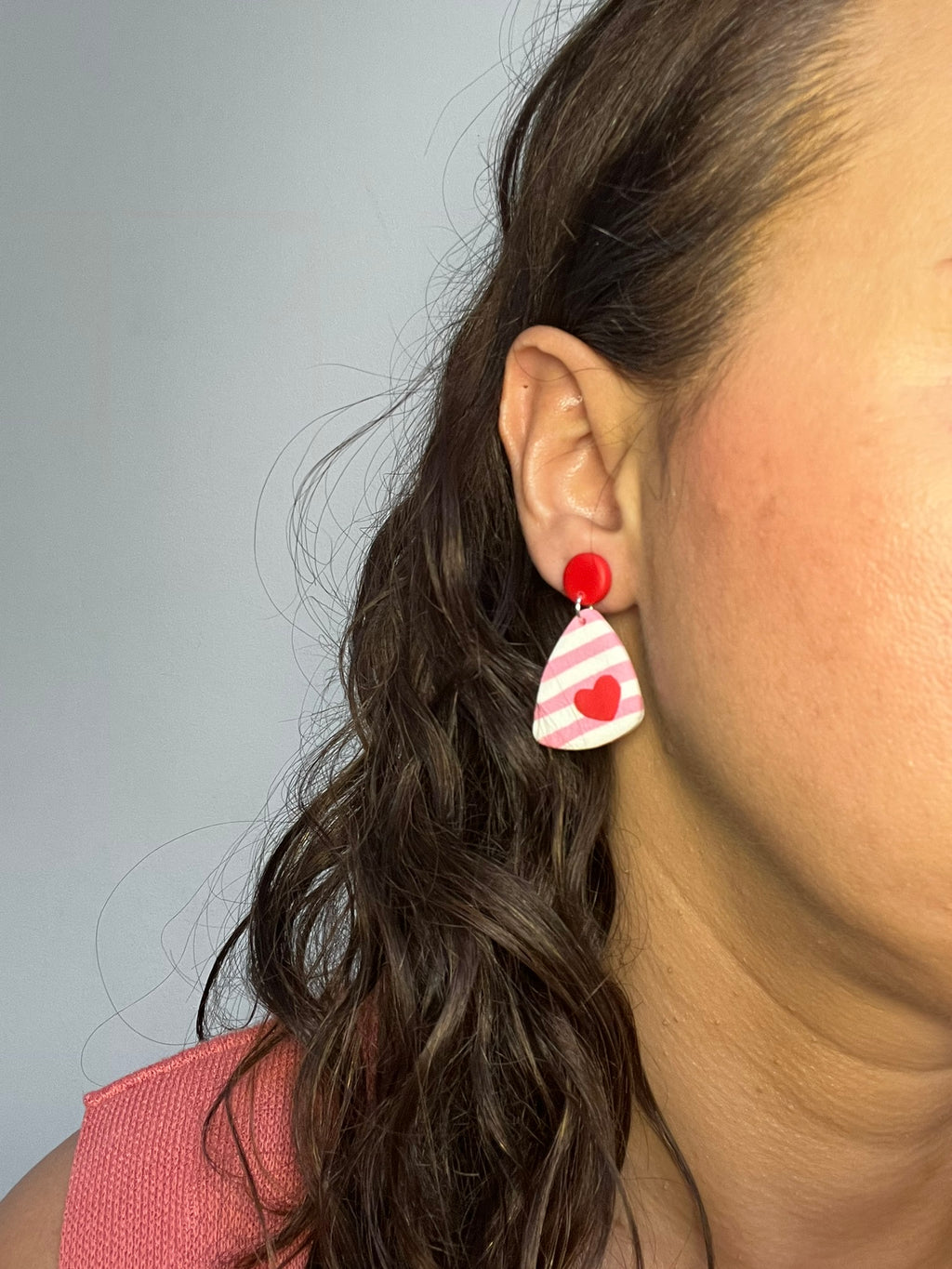 Pendientes Love Pop de arcilla polimérica en rosa, blanco y rojo puestos en la oreja